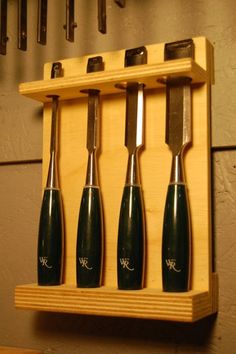 a set of knives mounted to a wooden shelf with hooks on the wall behind it