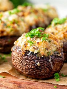 stuffed mushrooms with cheese and parsley on top sitting on a piece of parchment paper