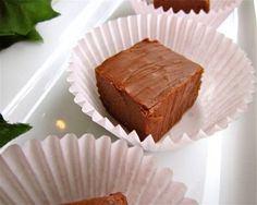 three pieces of chocolate cake sitting on top of white paper cups with green leaves in the background