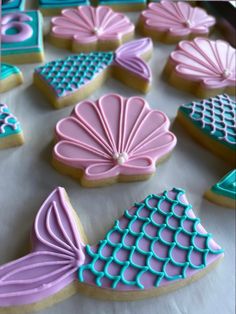 decorated cookies are displayed on a table with blue, pink and green icing in the shape of seashells