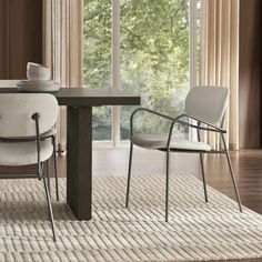 a dining room table with two chairs and a rug on the floor in front of it