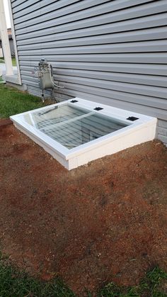 an outside hot tub in the ground next to a building with grass and dirt around it