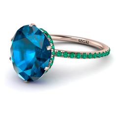 an oval blue topaz ring with green emeralds on the sides and gold band