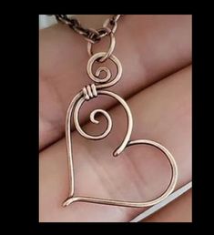 a heart shaped pendant is being held in someone's hand