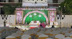 an outdoor wedding setup with white and pink flowers on the stage, surrounded by chairs