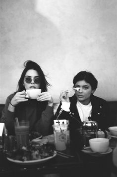 two women sitting at a table drinking coffee