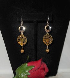 "Artisan long dangle earrings in both sterling silver and brass. The earrings start with a silver open center disk. Dangling below that is a brass disk with cutouts. Dangling at the bottom is a brass bead. Boho, big bold look, statement earrings. Hallmarks - The sterling disk is marked \"925 LT Indonesia and the brass disk is marked \"BRASS\". Ear wires were acid tested to be sterling silver. Measurements - About 2 3/4\" long by about 3/4\" wide. Condition - Very good. Comes gift wrapped in a sm Artistic Gold Jewelry With Ear Wire, Hallmarked Dangle Metal Earrings, Hallmarked Metal Dangle Earrings, Artisan Metal Chandelier Earrings For Gift, Artisan Metal Chandelier Earrings As Gift, Artistic Silver-colored Copper Earrings, Artistic Silver Copper Earrings, Brass Long Drop Chandelier Earrings As Gift, Artisan Gold Earrings For Anniversary