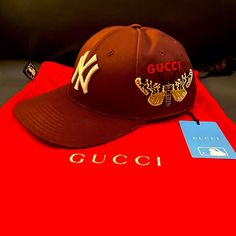 Good Condition Red/Burgundy Gucci Nyc Cap Comes With Dust Bag, Tags, Sticky Chip Designer Gucci Baseball Cap With Embroidered Logo, Gucci Brown Short Brim Hat, Brown Gucci Cap Hat, Gucci Casual Baseball Cap With Curved Brim, Luxury Gucci Baseball Cap, Casual Gucci Baseball Cap With Curved Brim, Gucci Brown Curved Brim Hat, Casual Gucci Hat With Embroidered Logo, Luxury Brown Hat With Embroidered Logo