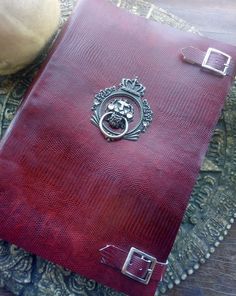 a red leather book sitting on top of a wooden table next to a planter