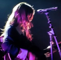 a woman with long hair playing guitar in front of a microphone on stage at a concert