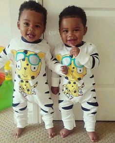 two young boys wearing matching onesuits and smiling for the camera