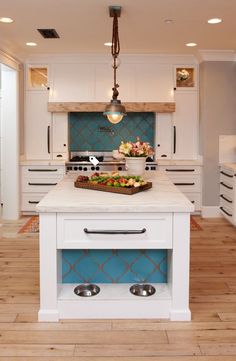 a large kitchen with white cabinets and blue backsplashing on the island counter