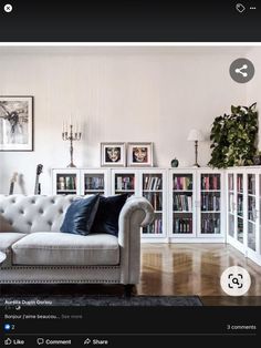 a living room filled with furniture and bookshelves next to a wall covered in pictures