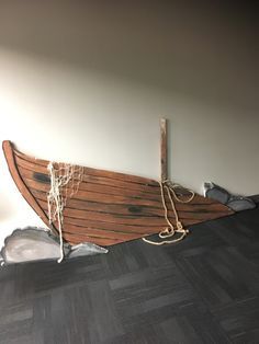 a wooden boat sitting on top of a hard wood floor next to a white wall