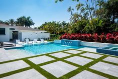 an outdoor pool with artificial grass in the middle and lounge chairs around it, surrounded by palm trees