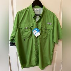 a green button up shirt hanging on a door with a tag attached to the chest