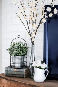 a vase with white flowers sitting on top of a wooden shelf next to a metal container