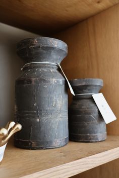 two metal containers sitting on top of a wooden shelf