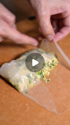 someone is cutting up some food on a table with a knife and plastic wrapper