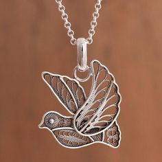 Peruvian artisan Nancy Quispe designs and handcrafts this beautiful pendant necklace of a dove inspired by its messages of peace faith and hope. The sterling silver dove is created with the filigree technique with graceful loops and swirls of ribbons of sterling silver forming the dove's feathers accentuated by a striking combination of finishes. Handmade Sterling Silver Bird-shaped Jewelry, Silver Bird Design Pendant Necklace, Sterling Silver Bird Necklace, Silver Bird-shaped Sterling Silver Necklace, Sterling Silver Bird Pendant Jewelry, Faith And Hope, Dove Necklace, Filigree Pendant Necklace, Styles Hairstyles