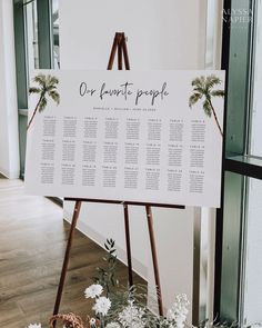 a sign that is on top of a wooden easel with flowers in front of it