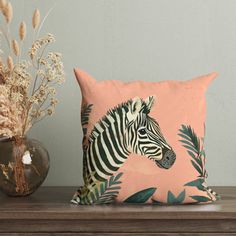 a pillow with a zebra on it sitting next to a vase filled with dried flowers