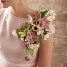 a woman in a dress holding a bouquet of flowers on her shoulder and looking at the camera