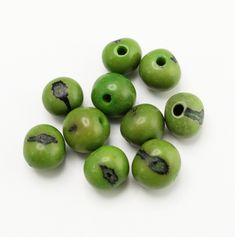 green beads with holes in them on a white surface