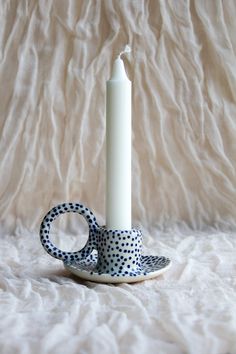 a polka dot cup and saucer with a candle