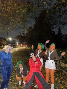 three people dressed in costumes posing for the camera at night with trees and street lights behind them