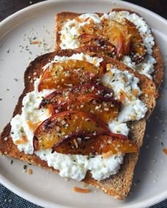 two pieces of toast with goat cheese and tomatoes on them sitting on a white plate