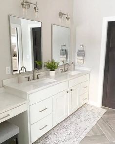 a bathroom with two sinks, mirrors and a bench in front of the sink area