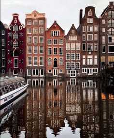 a boat traveling down a river next to tall buildings with lots of windows on each side