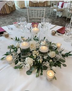 a centerpiece with candles and flowers on a white table cloth at a wedding reception