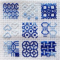 some blue and white embroidered designs on a piece of cloth with stitching in the middle