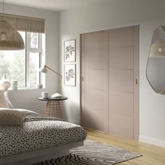 a bedroom with white walls and wooden floors has pink doors, beige furniture, and patterned bedding