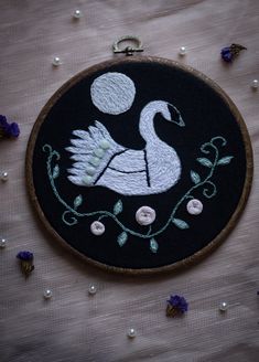 a black and white embroidered swan with flowers on it