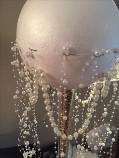 a large white ball with pearls hanging from it's sides on a stand in front of a wall