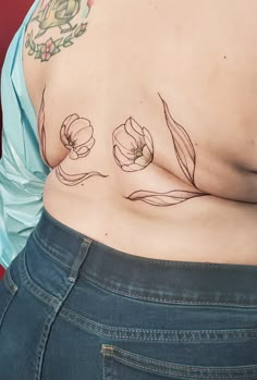 a woman's stomach with tattoos on it and flowers drawn on the side of her body