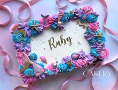 a heart shaped cake with pink, blue and purple icing that says ruby on it