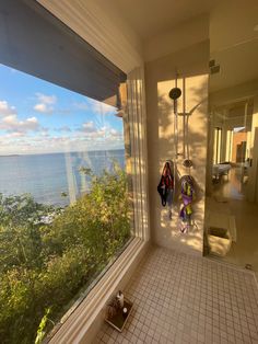 a bathroom with a large window looking out at the ocean and trees in front of it