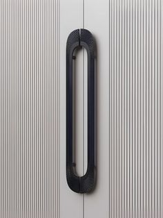 a black door handle on a white door with vertical lines in the wall behind it