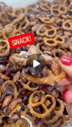 a person holding up a piece of food in front of a pile of pretzels