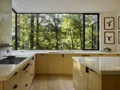 a kitchen with wooden cabinets and windows overlooking the trees outside in front of it is shown