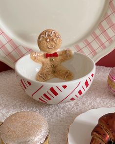 a small teddy bear sitting in a bowl on top of a table next to plates and cupcakes