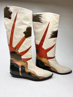 "Here are such a wonderful pair of vintage 80s boots. They are so graphic and cool. The color combination of the boots is really good also. They are all an off white leather with olive green appliques of faces in profile, an orange rising sun or a setting sun, and a modern design of gold and olive green. They are really a knock out, sure to get you noticed. The boots are made in Spain, are all leather, and are a size 6 1/2\". They are in great condition. There is a a tiny bit of wear to the back Retro White Leather Boots, White Boots Dress, Painted Leather Boots, Circus Boots, 80s Boots, Mismatched Shoes, Painted Boots, Vintage Pop Art, Boots Dress