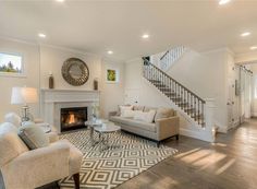 a living room filled with furniture and a fire place in front of a stair case