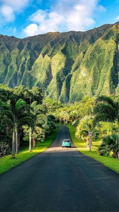 a car is driving down the road in front of mountains