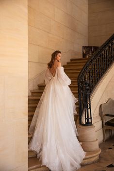 a woman in a wedding dress is standing on the stairs with her back to the camera