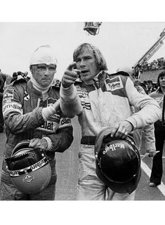 two men standing next to each other in front of a group of people on a race track